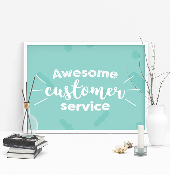 A green poster that says 'Awesome customer service' in white in a white frame. Poster is on a table next to an unlit white candle, 2 white/brown flowers, a white vase with plant limbs and 4 stacked black books under a clear vase containing 3 scent sticks. Hatch thrives to offer outstanding customer service.